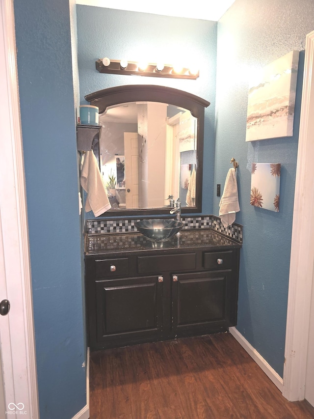 bathroom featuring baseboards, wood finished floors, and vanity