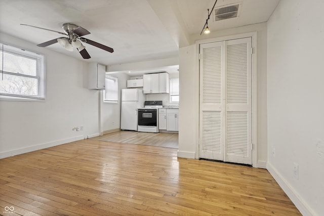 interior space featuring light wood-style flooring, white appliances, white cabinetry, visible vents, and baseboards