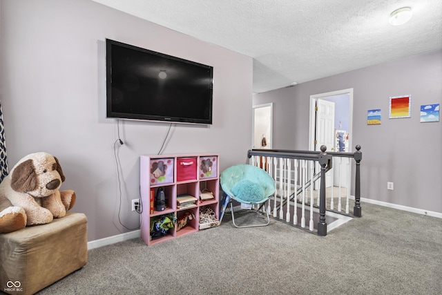 playroom with a textured ceiling, baseboards, and carpet flooring