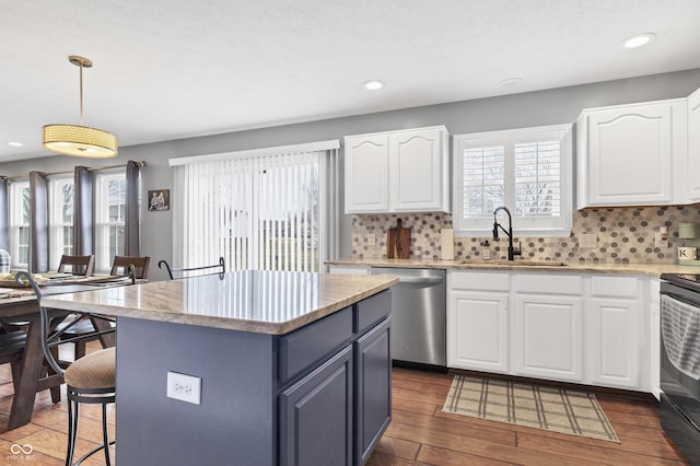 kitchen with a kitchen island, white cabinetry, a sink, and stainless steel dishwasher