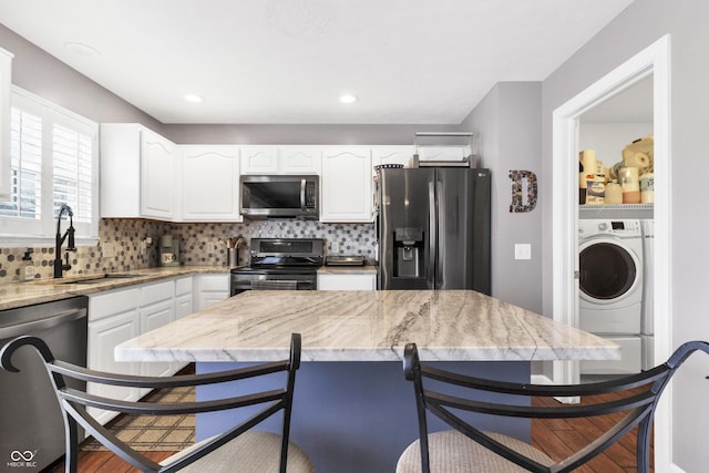 kitchen featuring appliances with stainless steel finishes, independent washer and dryer, a sink, and tasteful backsplash