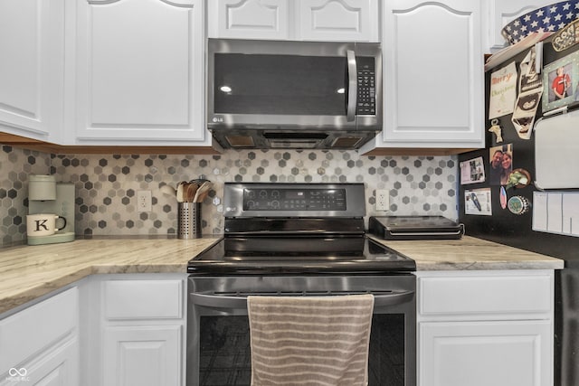 kitchen featuring stainless steel appliances, white cabinetry, and backsplash