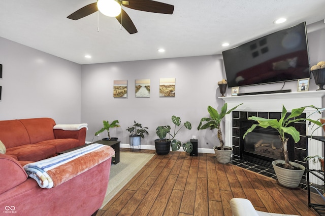 living area featuring recessed lighting, baseboards, a tiled fireplace, and hardwood / wood-style floors