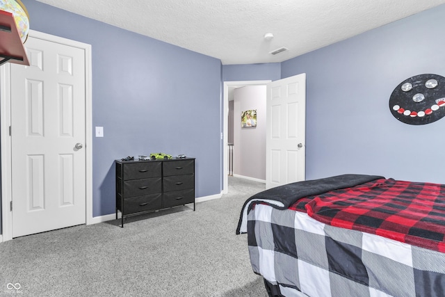 carpeted bedroom featuring a textured ceiling, visible vents, and baseboards