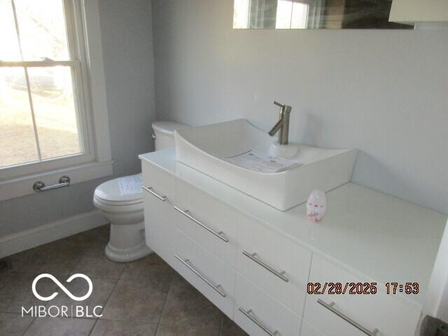 half bathroom featuring toilet, tile patterned flooring, and vanity