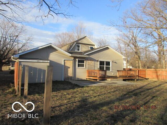 rear view of property featuring a yard, fence, and a deck