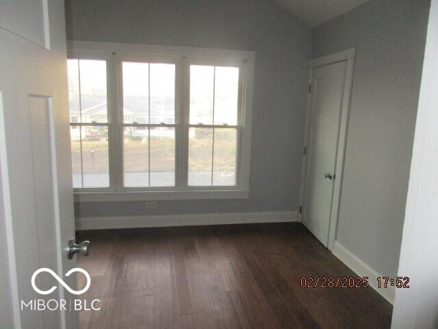 empty room with dark wood-type flooring and baseboards