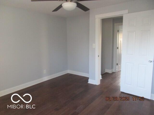 empty room featuring ceiling fan, dark wood finished floors, and baseboards