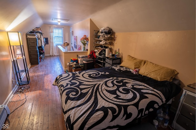 bedroom with lofted ceiling, baseboards, and hardwood / wood-style flooring