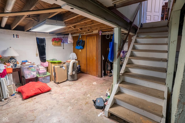 unfinished basement with concrete block wall and stairs