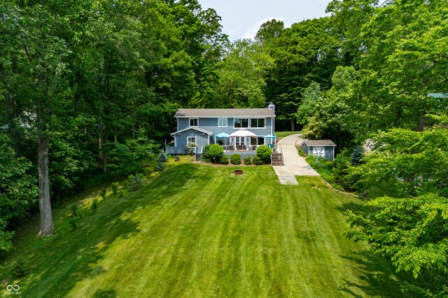 7600 N Blue Heron Dr, Unionville, IN 47468 - view of front of house with covered porch, a front lawn, a wooded view, and a chimney