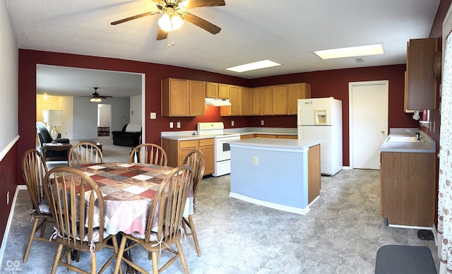 kitchen with under cabinet range hood, white appliances, a sink, a kitchen island, and light countertops