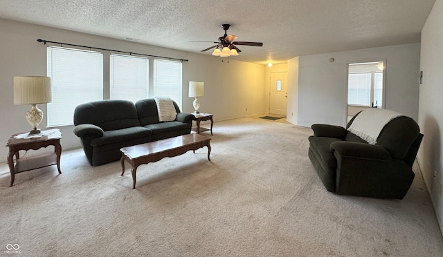 living area featuring light carpet, a textured ceiling, and a healthy amount of sunlight