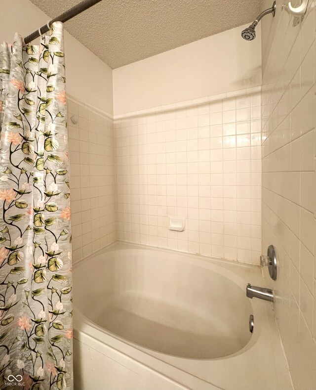 full bathroom with a textured ceiling and shower / bath combo with shower curtain