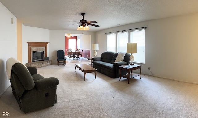 carpeted living room with a fireplace, a textured ceiling, baseboards, and ceiling fan