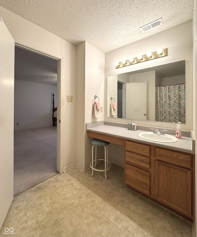 bathroom featuring baseboards, visible vents, a textured ceiling, and vanity