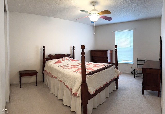 bedroom featuring a ceiling fan, a textured ceiling, and light colored carpet