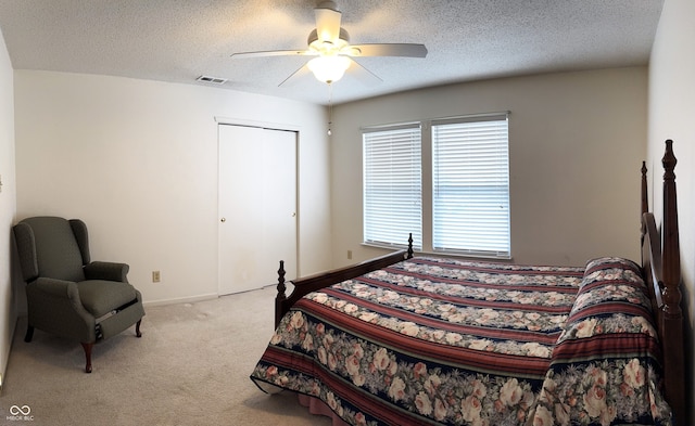 bedroom featuring a ceiling fan, visible vents, a textured ceiling, and light colored carpet