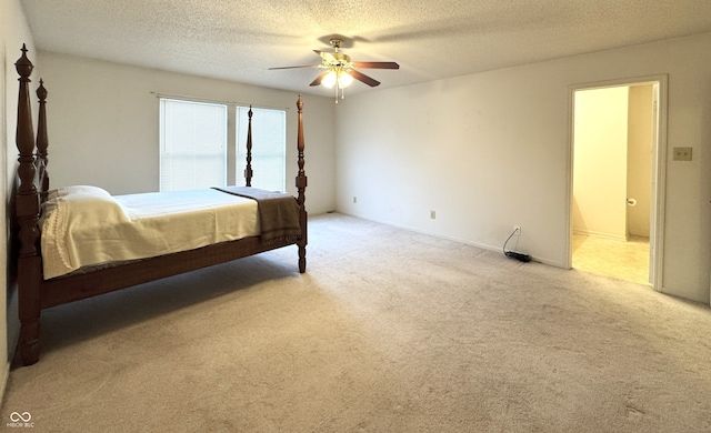 bedroom featuring ceiling fan, ensuite bathroom, a textured ceiling, and light colored carpet