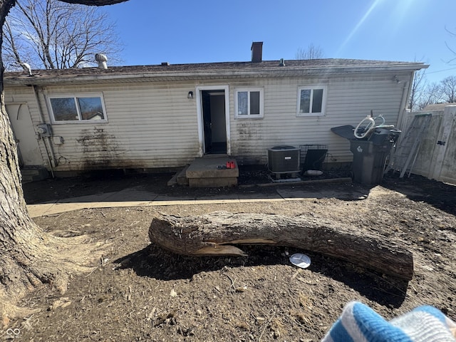 rear view of house with a chimney, fence, and central air condition unit