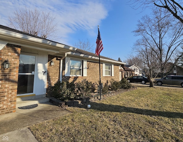 view of side of property featuring a yard and brick siding