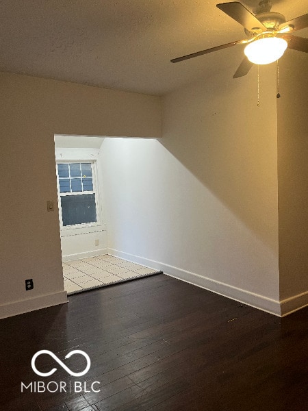 interior space with a ceiling fan, baseboards, and dark wood-style flooring