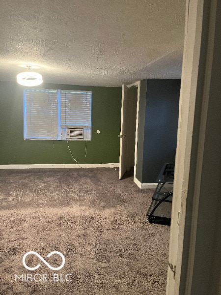 interior space featuring cooling unit, carpet flooring, a textured ceiling, and baseboards