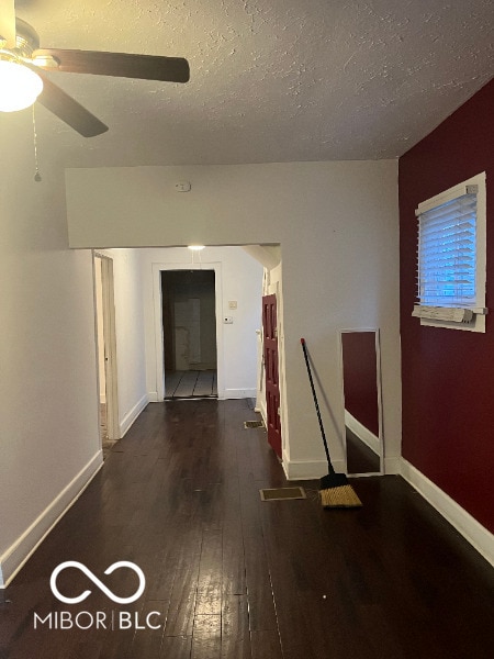 unfurnished room with hardwood / wood-style flooring, a ceiling fan, baseboards, and a textured ceiling