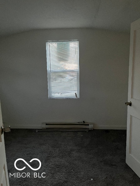 unfurnished room featuring a baseboard heating unit and carpet flooring