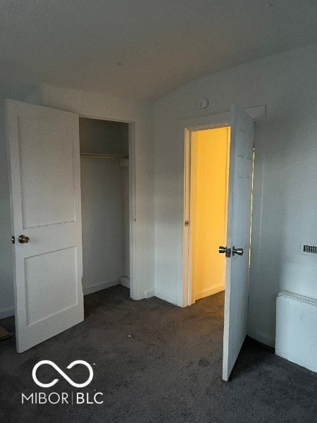 unfurnished bedroom featuring a closet and dark carpet