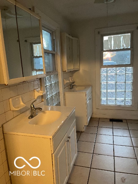 kitchen with light countertops, decorative backsplash, white cabinets, a sink, and light tile patterned flooring