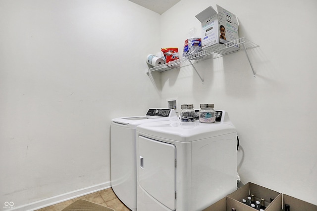 clothes washing area with washing machine and dryer, laundry area, baseboards, and light tile patterned floors