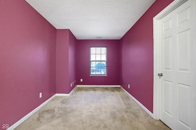 empty room with carpet, visible vents, baseboards, and a textured ceiling