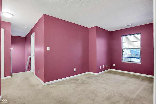 unfurnished room featuring a textured ceiling, carpet, visible vents, and baseboards