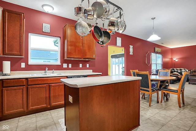 kitchen with brown cabinets, a kitchen island, light countertops, and a sink