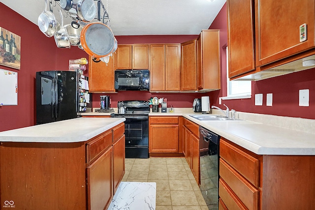 kitchen with brown cabinetry, a kitchen island, light countertops, black appliances, and a sink