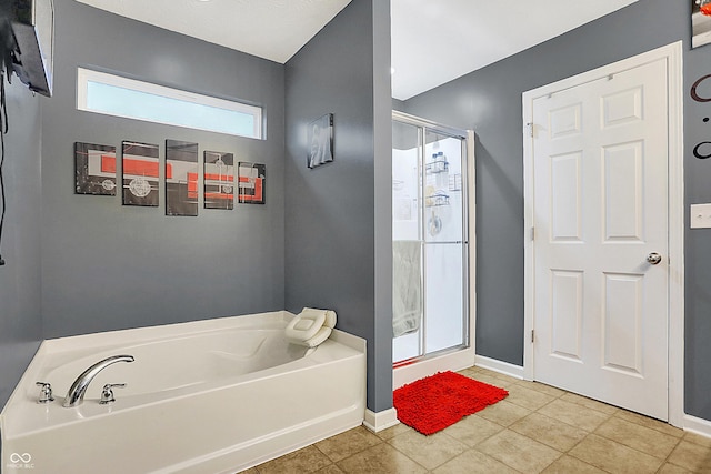 full bath featuring a stall shower, a garden tub, baseboards, and tile patterned floors