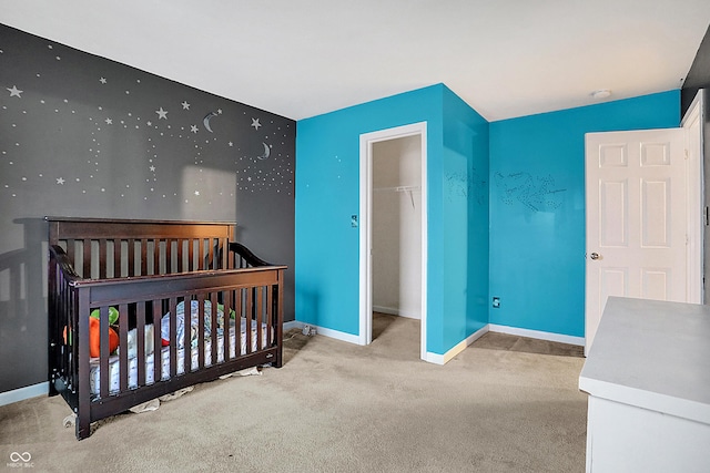 carpeted bedroom featuring a crib and baseboards