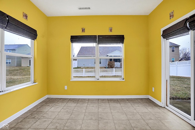 spare room with light tile patterned flooring, visible vents, and baseboards