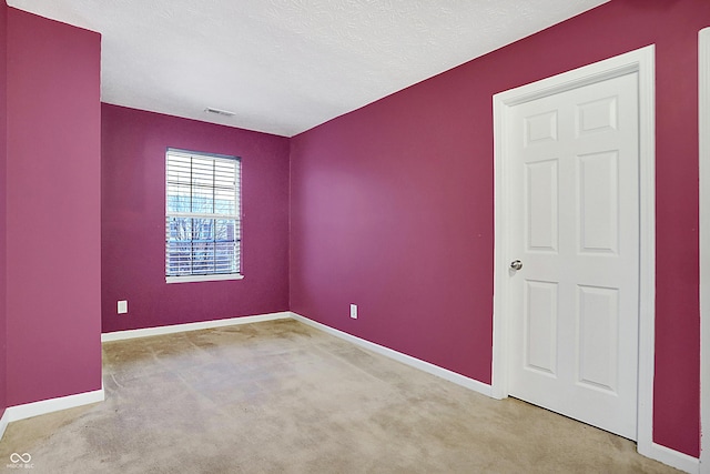 unfurnished room with carpet floors, visible vents, a textured ceiling, and baseboards