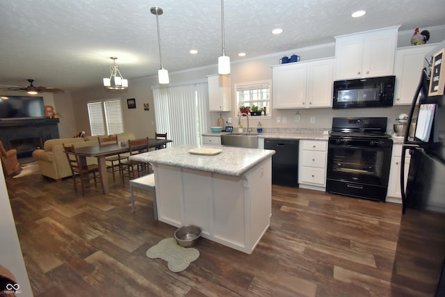 kitchen with a kitchen island, dark wood finished floors, a sink, and black appliances