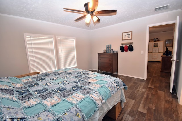 bedroom featuring a textured ceiling, wood finished floors, visible vents, baseboards, and ornamental molding