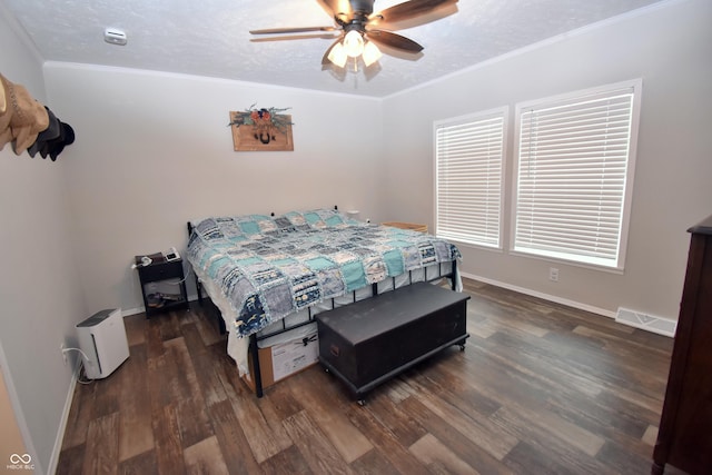 bedroom with baseboards, visible vents, wood finished floors, crown molding, and a textured ceiling