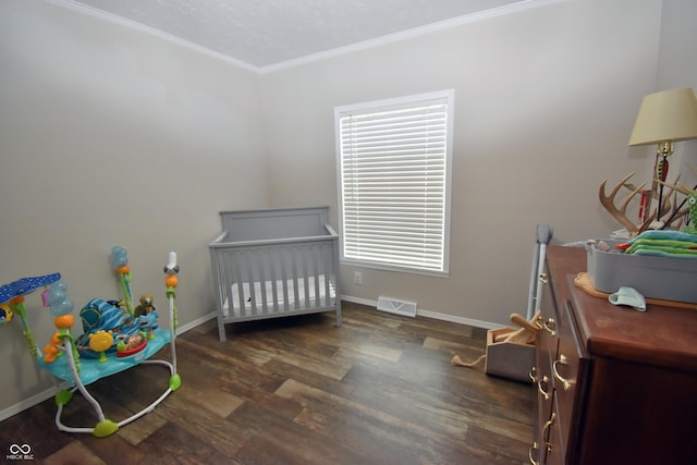 bedroom with ornamental molding, wood finished floors, visible vents, and baseboards