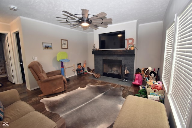 living room featuring ornamental molding, a textured ceiling, a fireplace with flush hearth, and wood finished floors