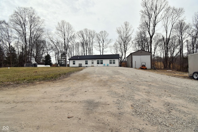 view of front of house with a garage, dirt driveway, and an outdoor structure