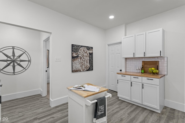 kitchen featuring light wood finished floors, tasteful backsplash, and wooden counters