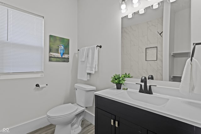 full bathroom featuring toilet, vanity, wood finished floors, tiled shower, and baseboards