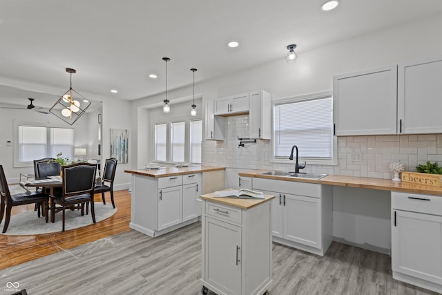 kitchen with plenty of natural light, light wood-style flooring, wood counters, and a sink