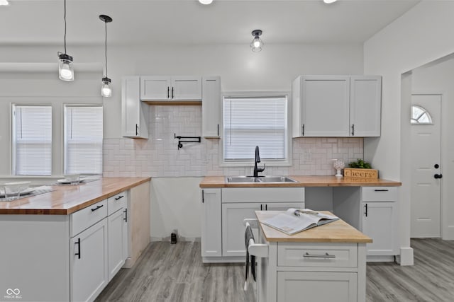 kitchen featuring light wood finished floors, butcher block countertops, a sink, and decorative backsplash